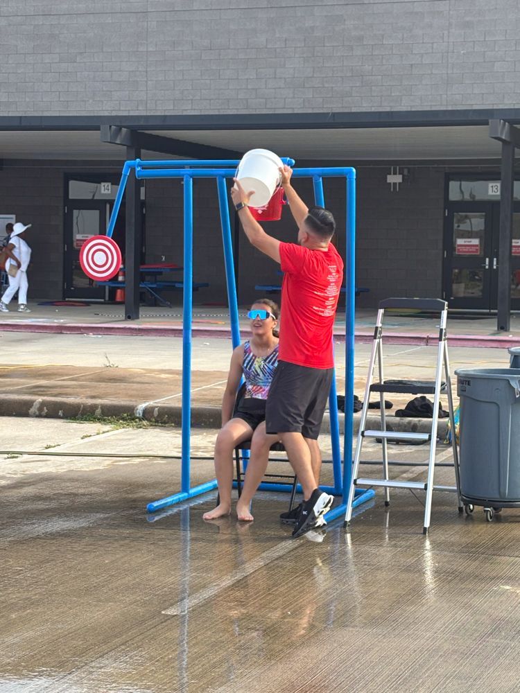 A man is pouring water on a woman sitting on a swing.