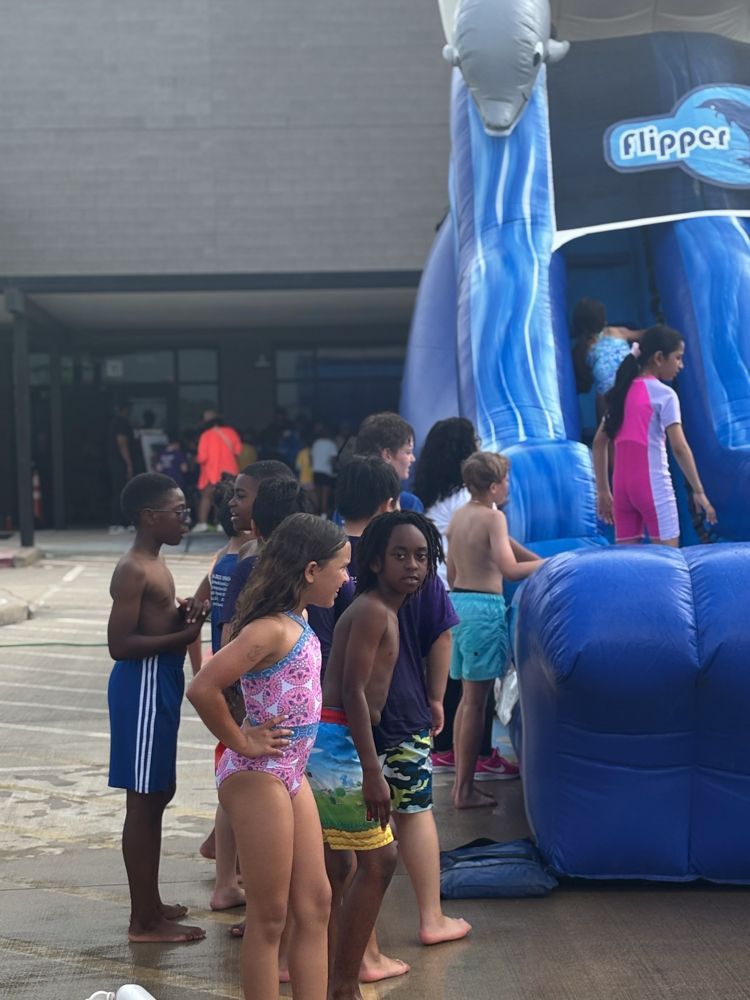 A group of children are standing in front of an inflatable water slide.