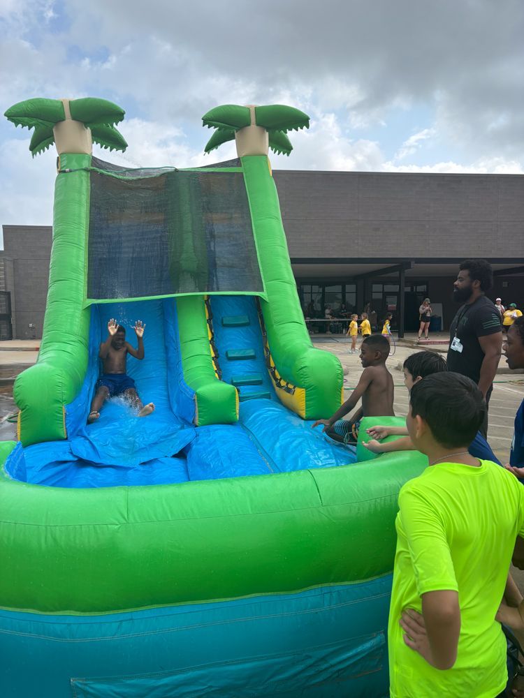 A group of children are playing on an inflatable water slide.