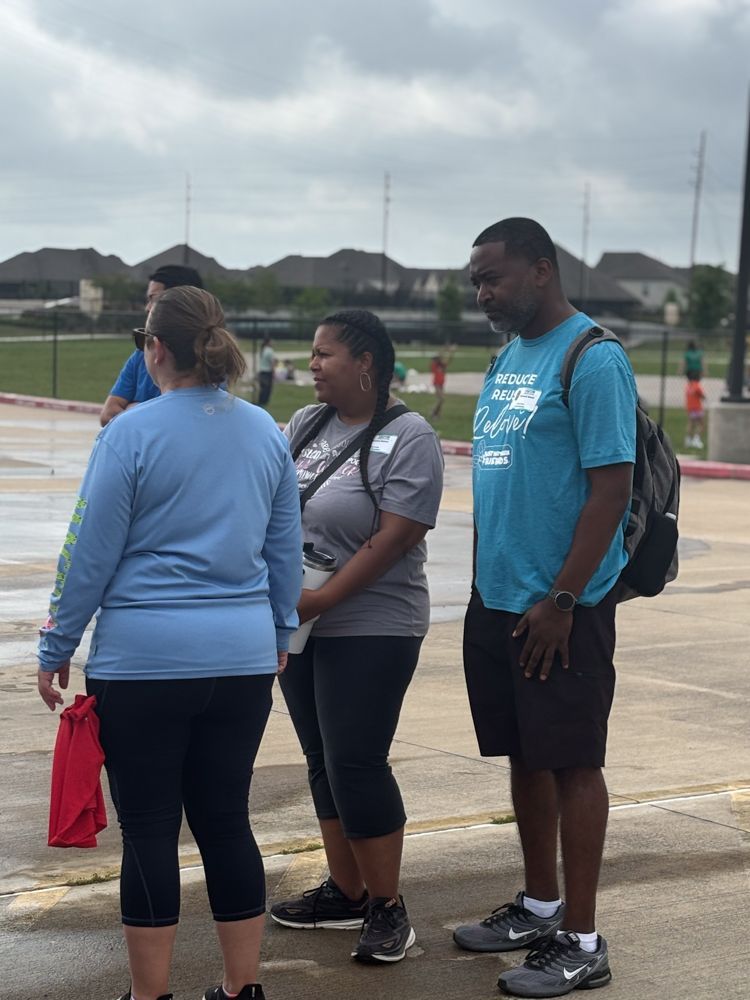 A man and two women are standing next to each other in a parking lot.