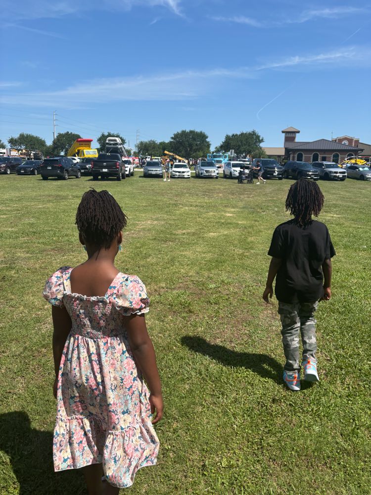 A boy and a girl are walking in a grassy field.