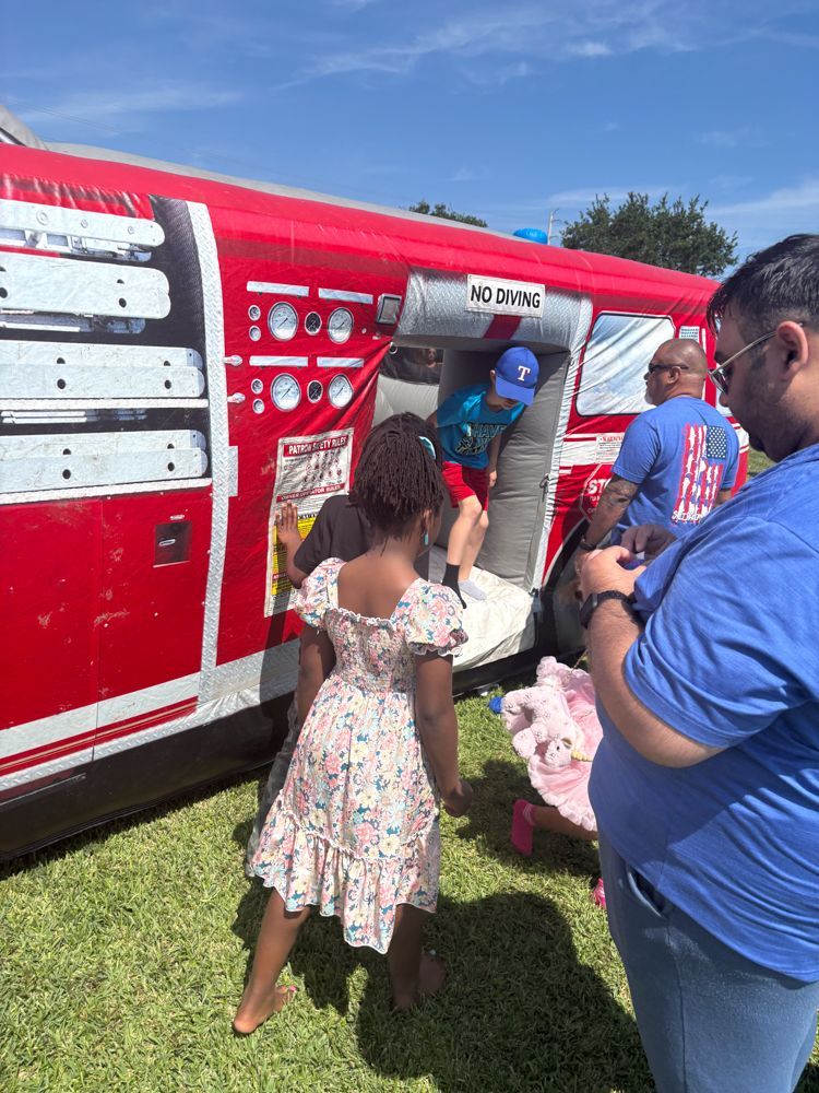 A little girl is standing in front of an inflatable fire truck.