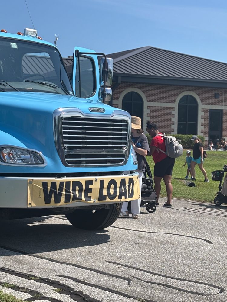 A blue truck with a yellow sign on the front that says `` wide load ''.