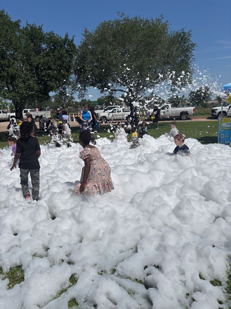 A group of children are playing in a pile of foam in a park.