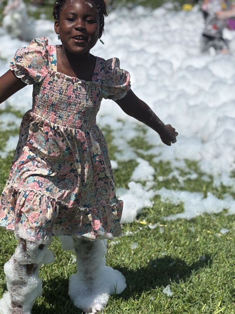 A little girl in a dress is standing in a field of foam.