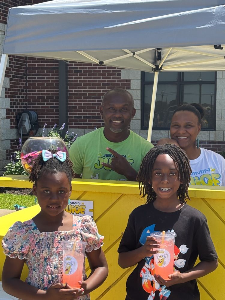 A man and two children are standing in front of a lemonade stand