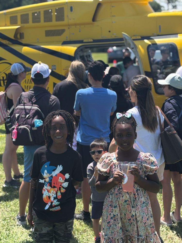 A group of people standing in front of a yellow helicopter