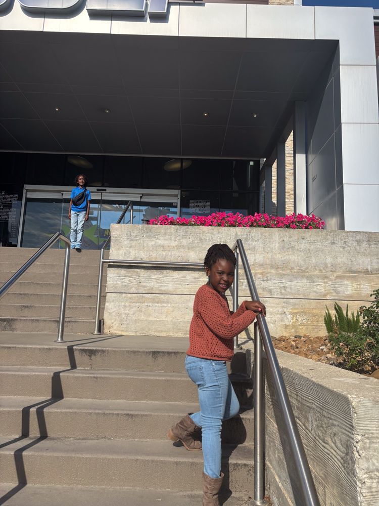 A little girl is standing on a set of stairs in front of a building.
