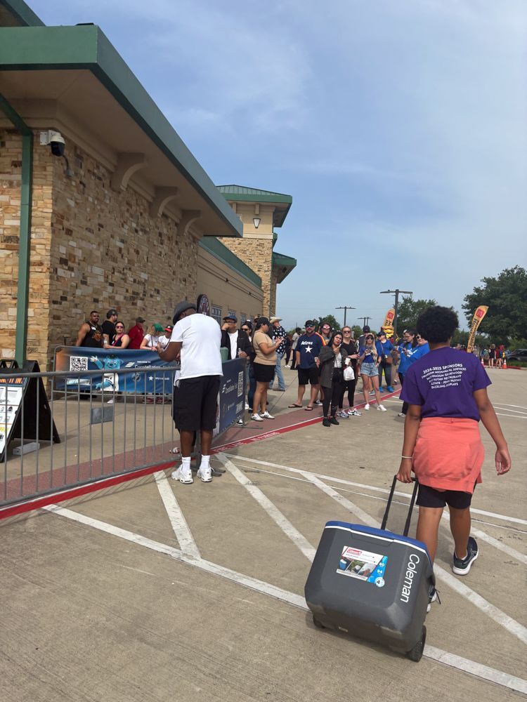A woman is pulling a cooler in a parking lot.