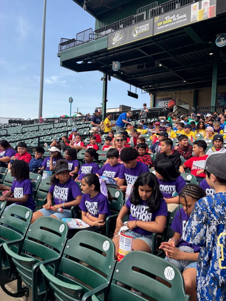 A group of children are sitting in the stands of a baseball stadium.