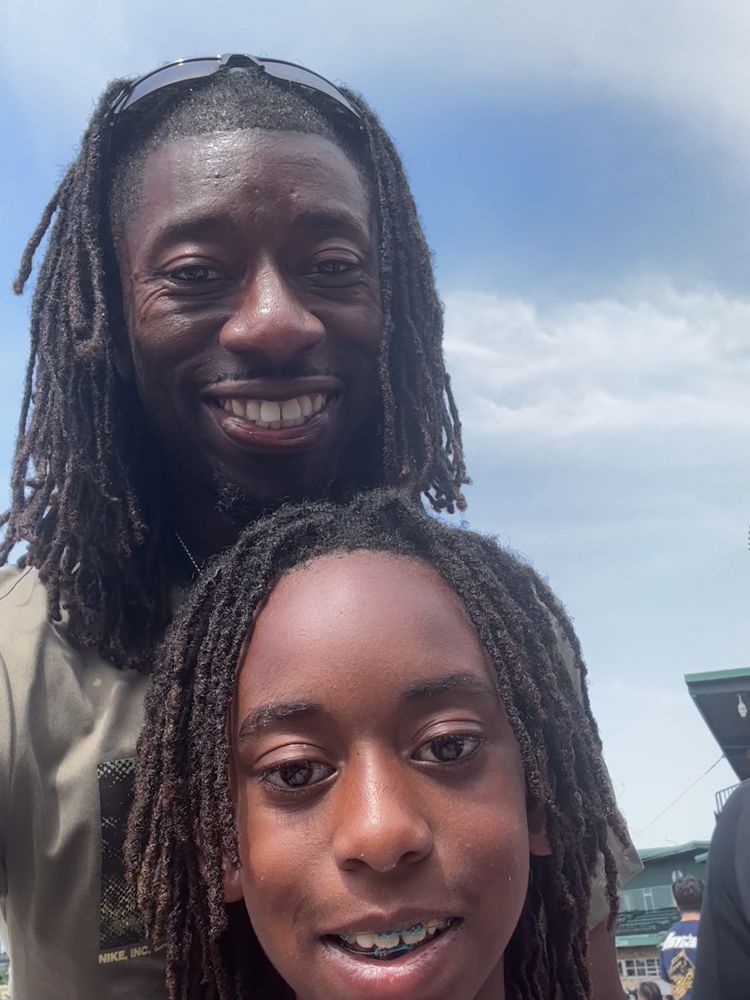 A man and a boy with dreadlocks are smiling for the camera.