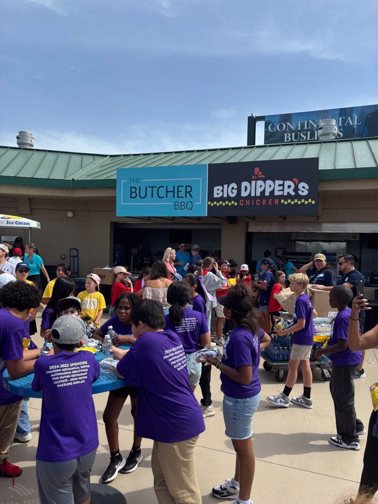A group of people in purple shirts are standing in front of a building.
