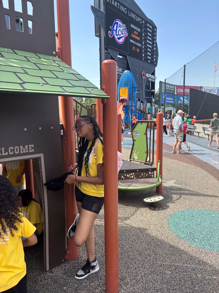 A girl in a yellow shirt is standing in a playground.