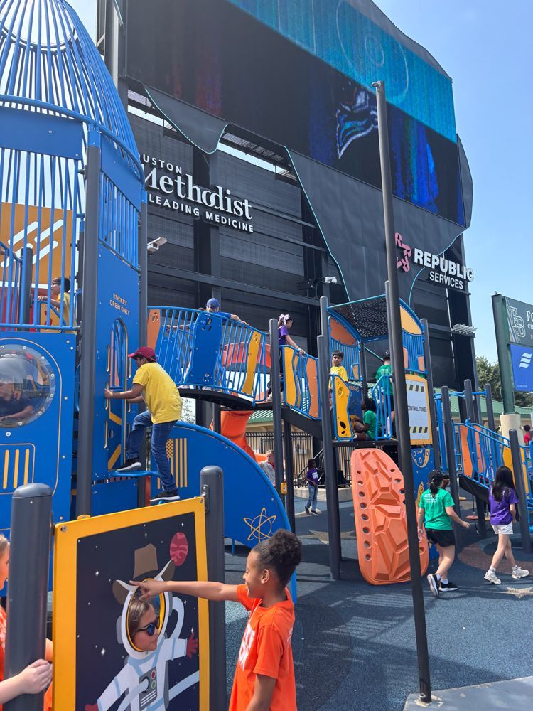 Children are playing in a playground in front of a building that says the methodist