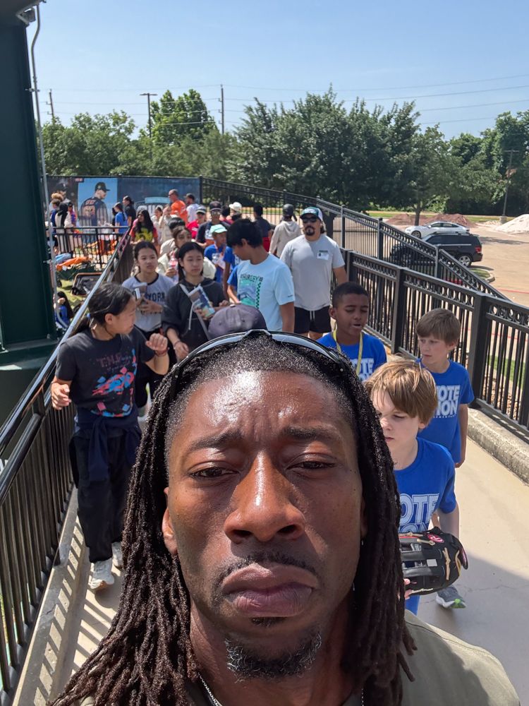 A man with dreadlocks is standing in front of a crowd of people.
