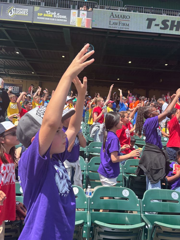 A group of people are standing in a stadium watching a baseball game.