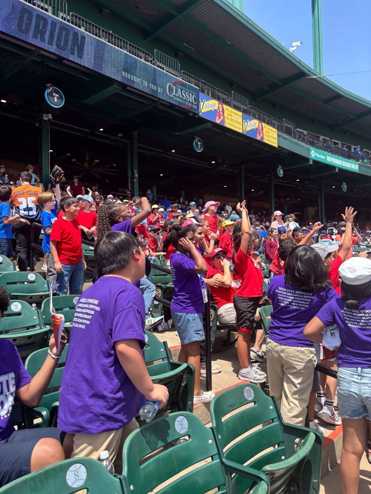 A group of people are sitting in a stadium with their hands in the air.