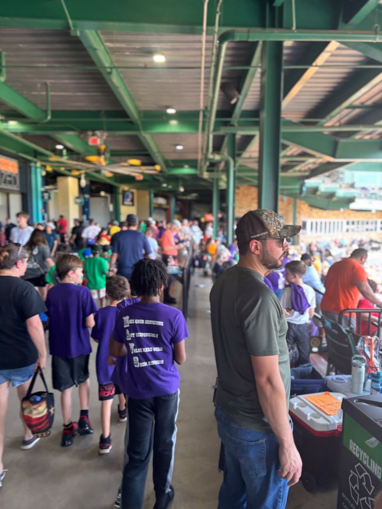 A group of people are standing in a stadium waiting for a game to start.