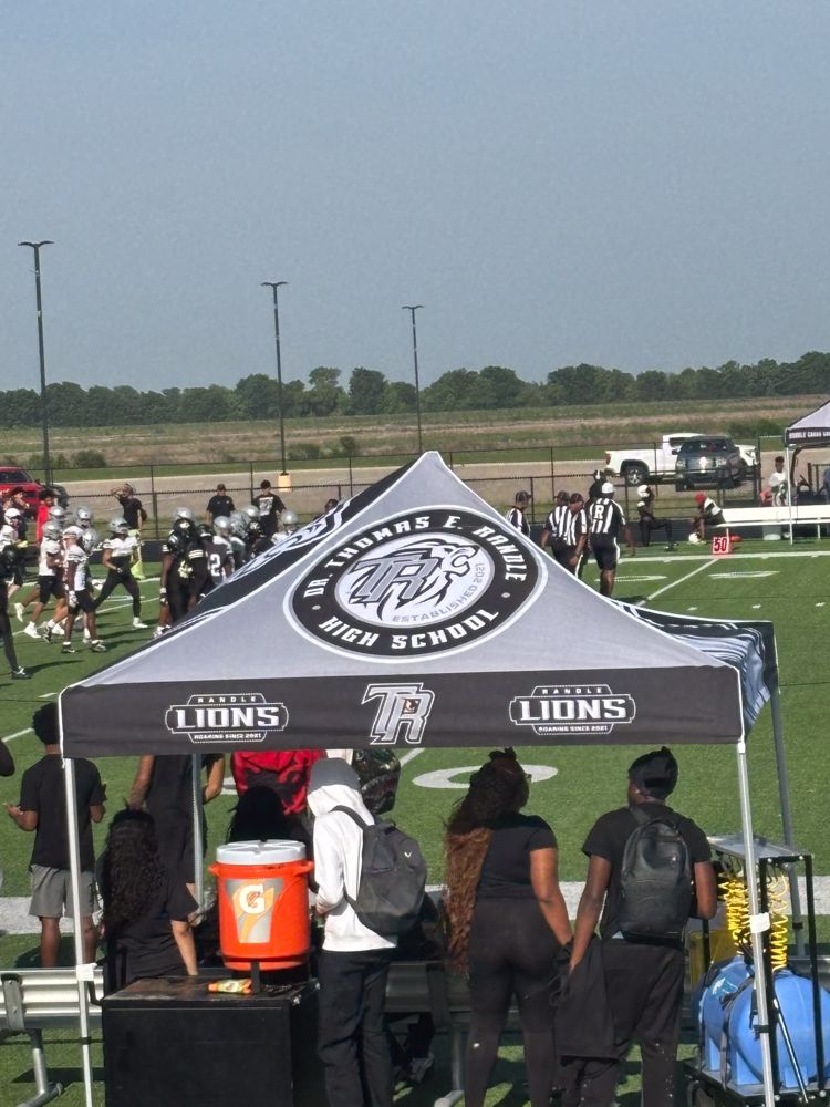 A group of people standing under a tent that says lions on it