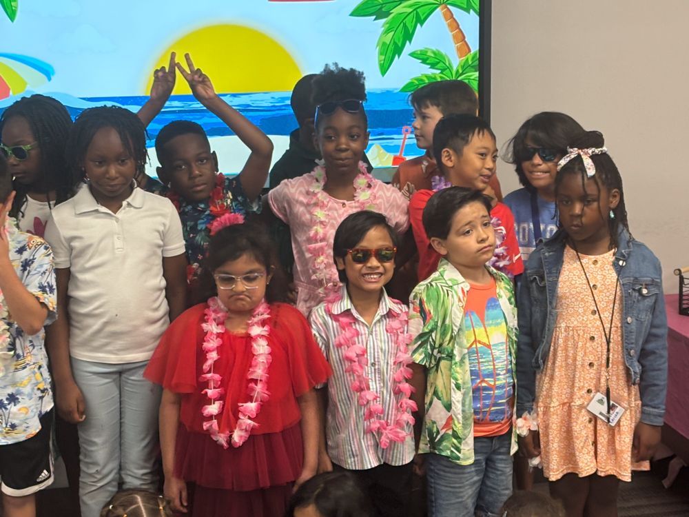 A group of children are posing for a picture in front of a screen.
