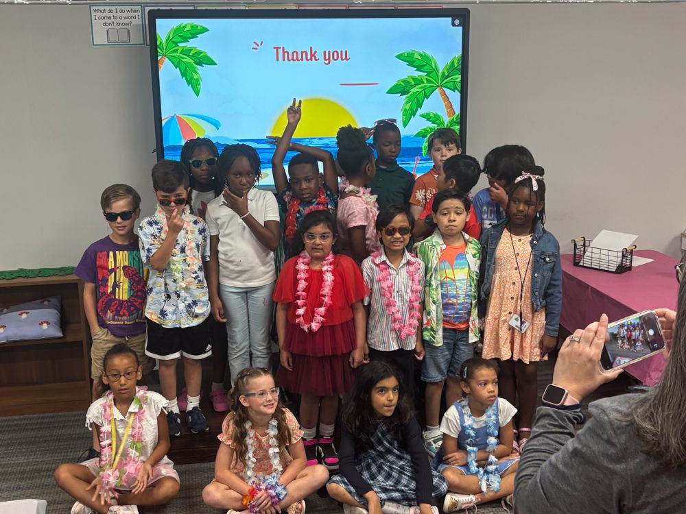 A group of children are posing for a picture in front of a screen that says thank you