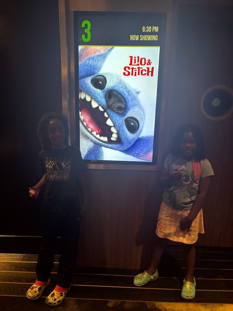 Two girls standing in front of a sign that says lilo & stitch