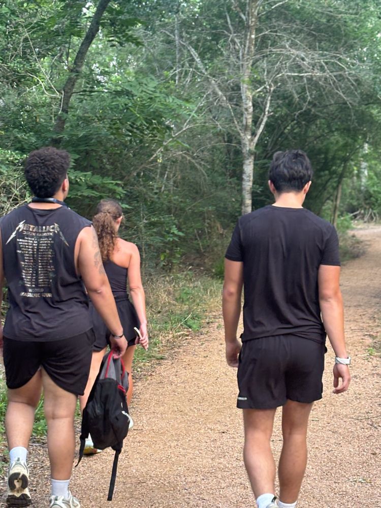 A group of people are walking down a dirt path in the woods.