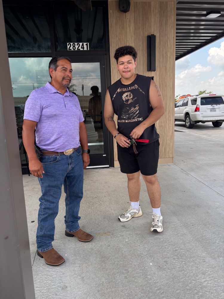 A man and a boy are standing in front of a building.