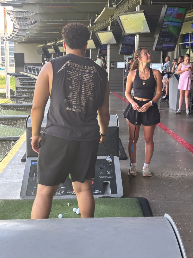 A man and a woman are standing on a golf course.