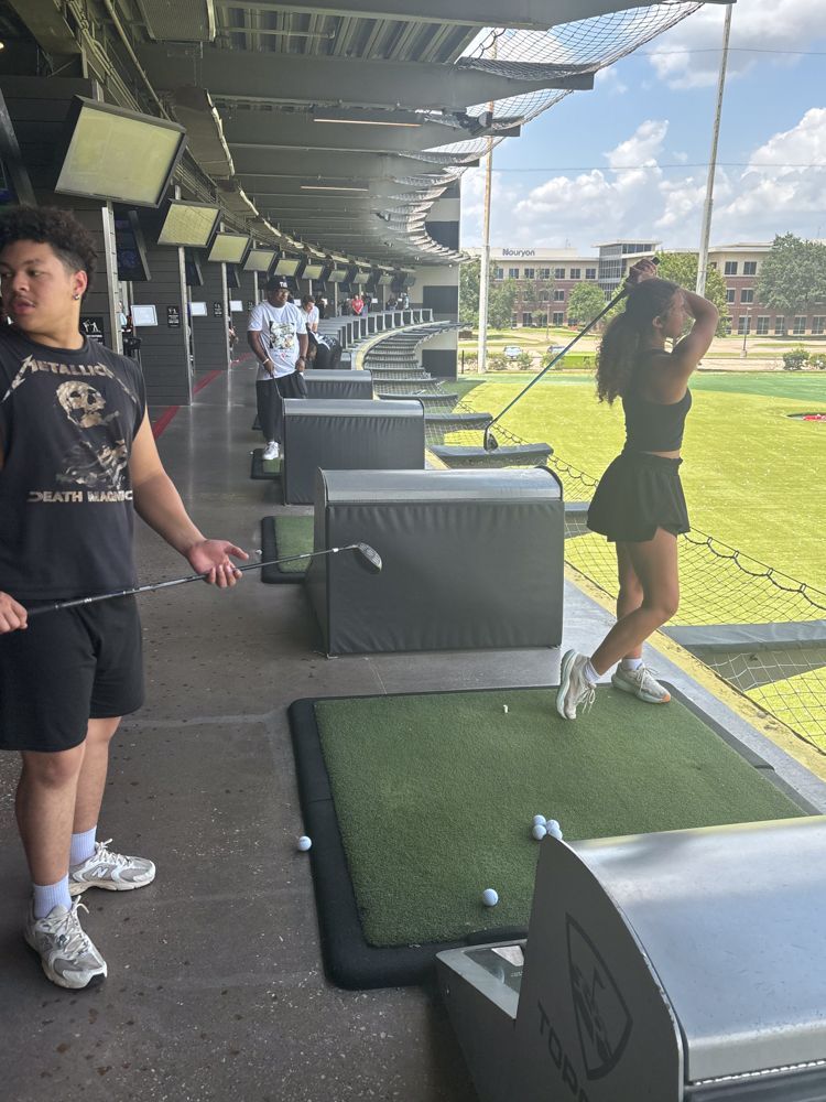 A man and a woman are playing golf at a driving range.