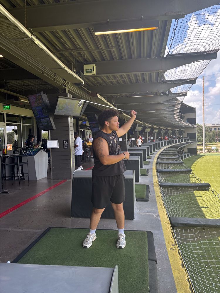 A man is standing on a golf course holding a golf club.