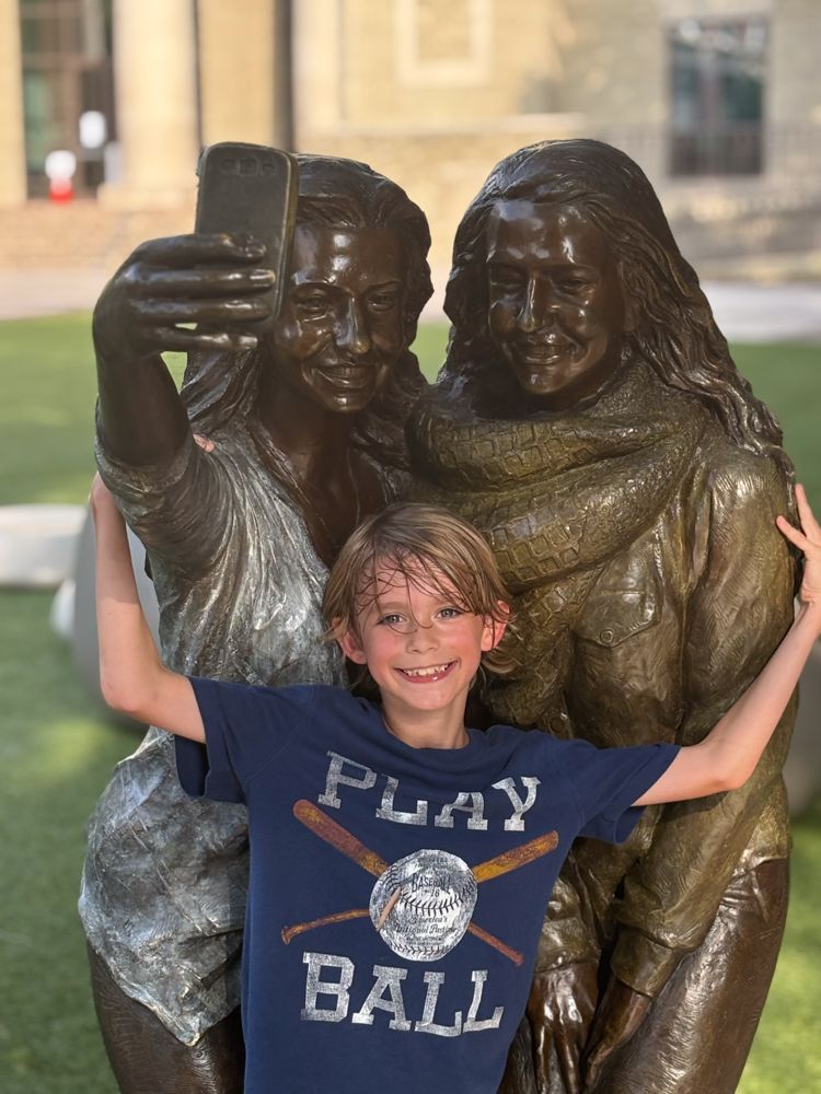 A young boy is taking a selfie in front of a statue.