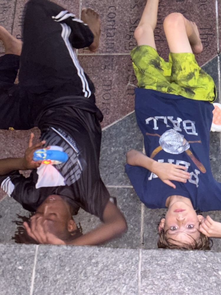 Two boys laying on their backs with one wearing a ball shirt
