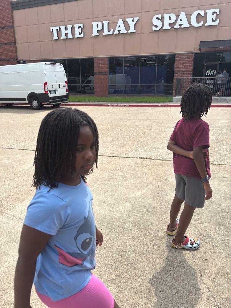 Two children are standing in front of the play space