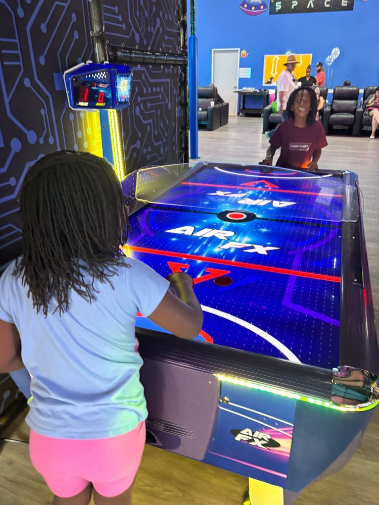 A little girl is playing a game of air hockey