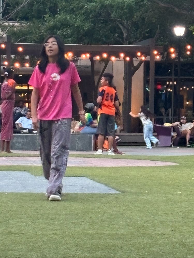 A girl in a pink shirt is walking in a park
