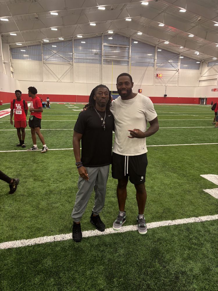 Two men are standing next to each other on a football field.