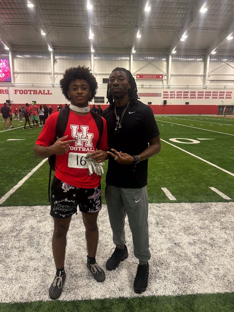 Two men are standing next to each other on a football field.
