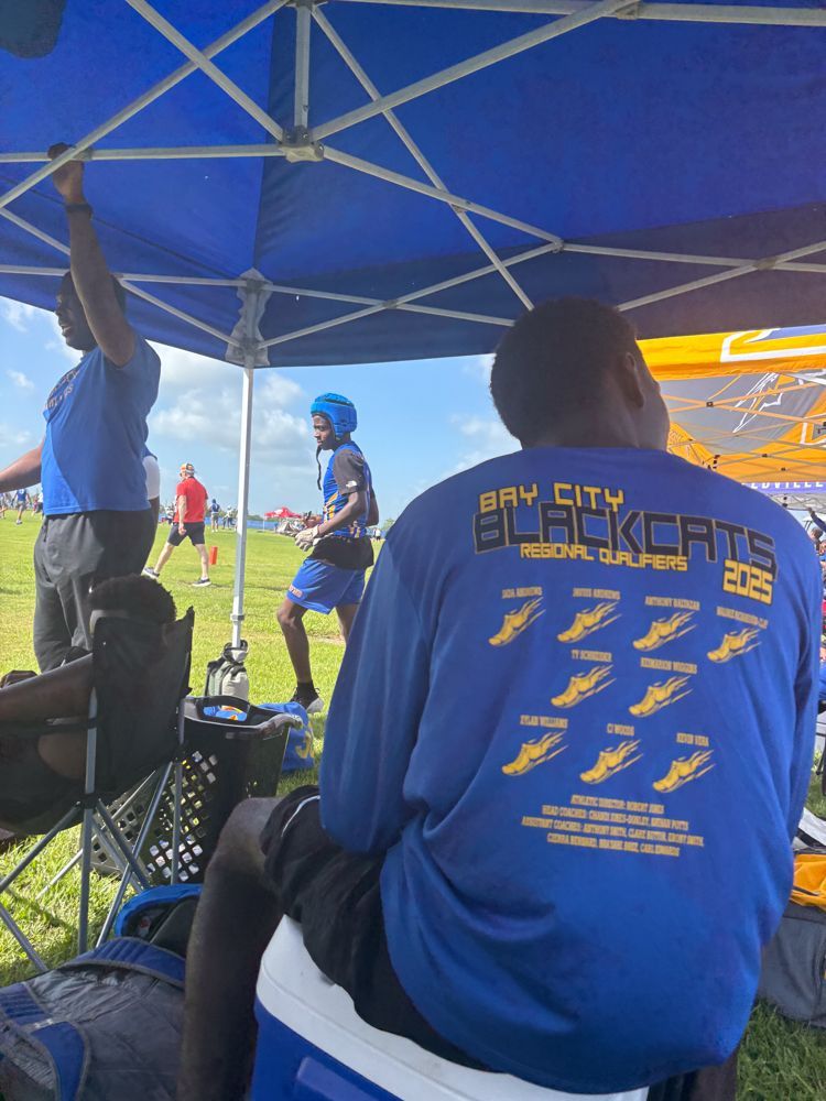 A man wearing a blue shirt that says bay city black cats