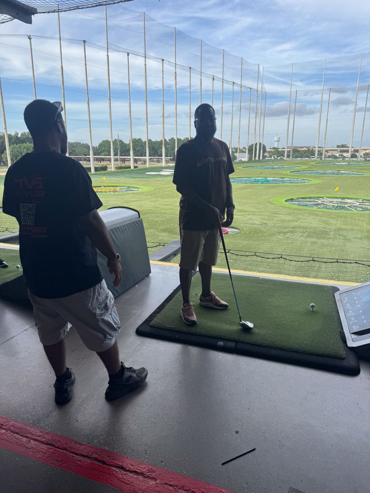 Two men are playing golf on a driving range.
