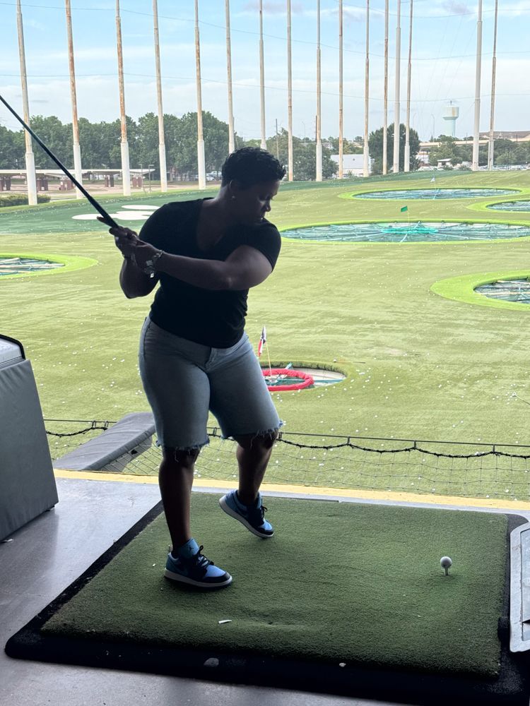A woman is swinging a golf club on a golf course.
