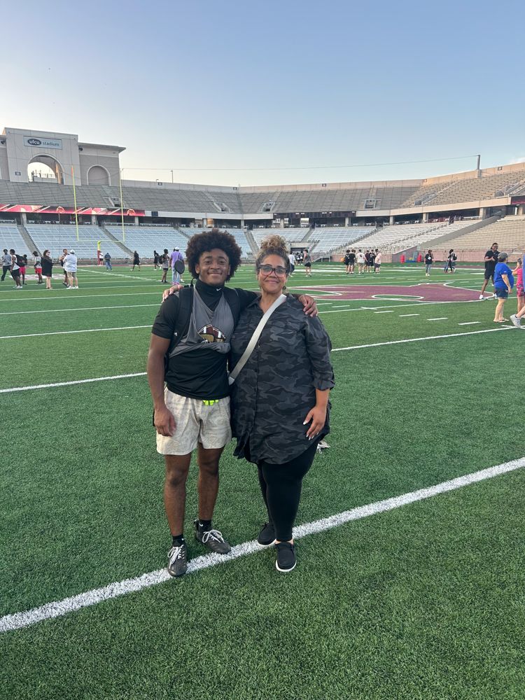 A man and a woman are standing on a football field.