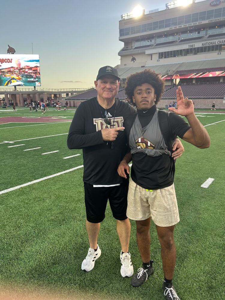 A man and a boy are posing for a picture on a football field.