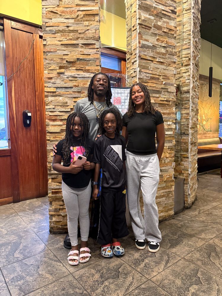 A family is posing for a picture in front of a stone wall.