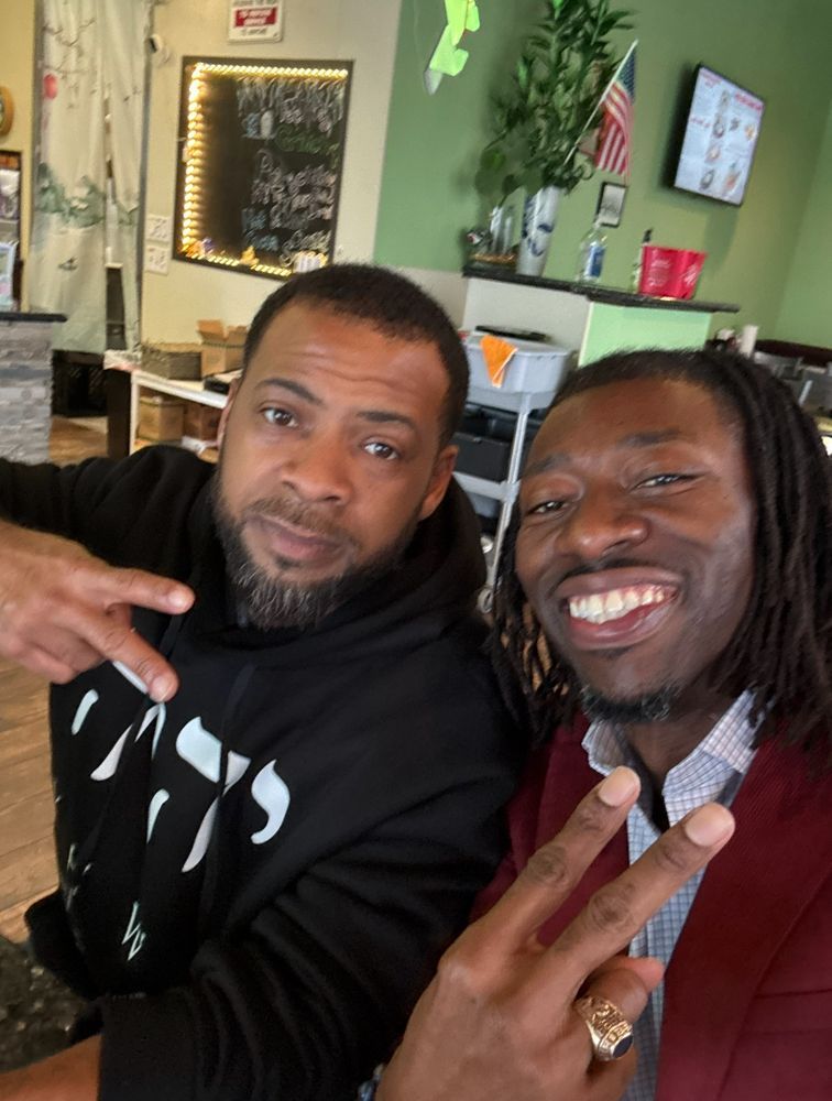 Two men posing for a picture with one wearing a hoodie that says ' 1776 ' on it