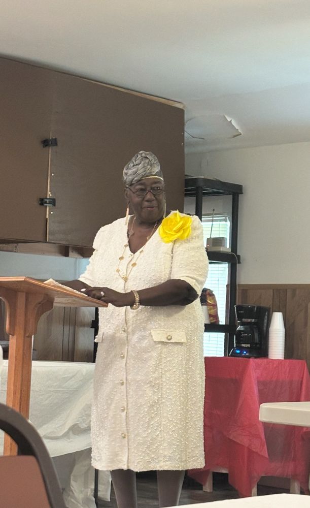 A woman in a white dress is standing at a podium giving a speech.