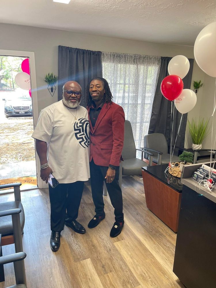 Two men are standing next to each other in a room with balloons.