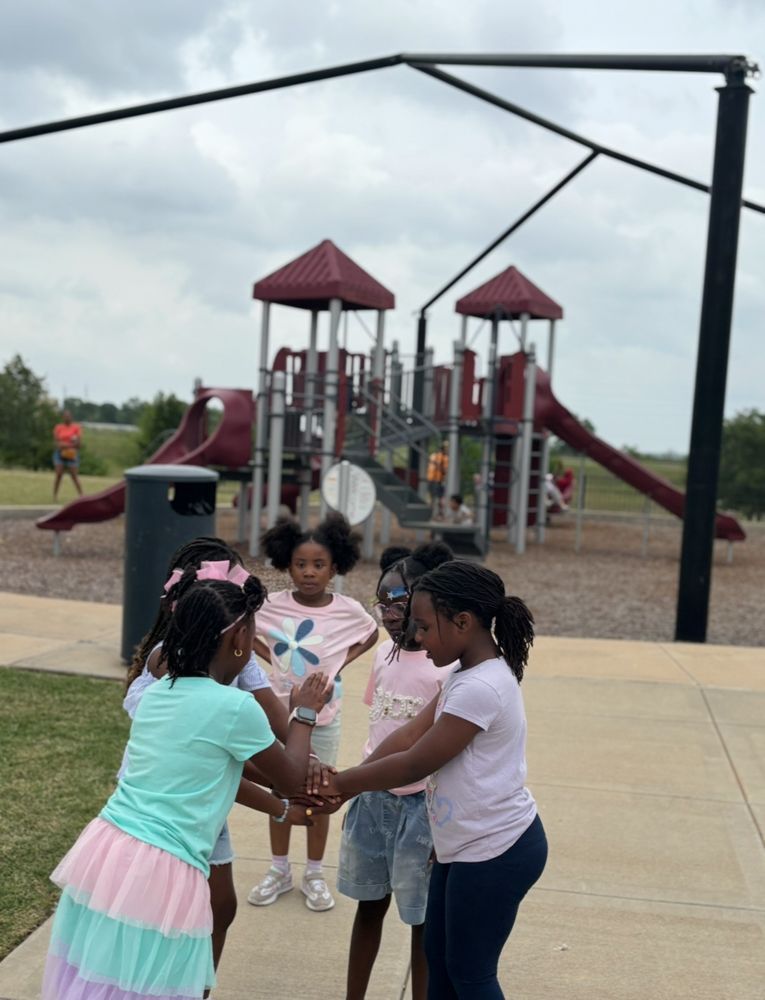 A group of young girls are shaking hands in front of a playground