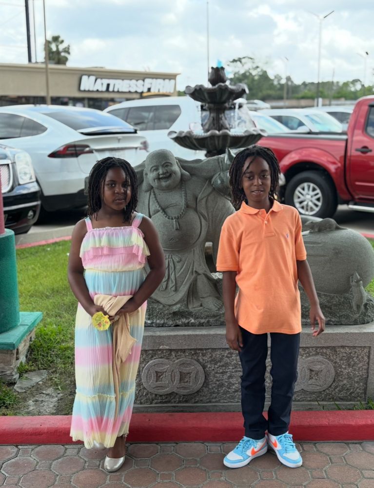 A boy and a girl are standing in front of a fountain.