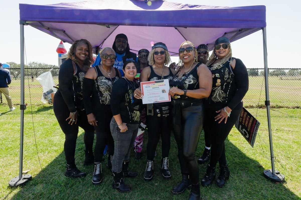 A group of women are posing for a picture under a purple tent.